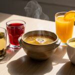 Five science-backed healthy drinks for joint and bone health displayed on wooden table including green tea, tart cherry juice, bone broth, fortified orange juice, and turmeric golden milk